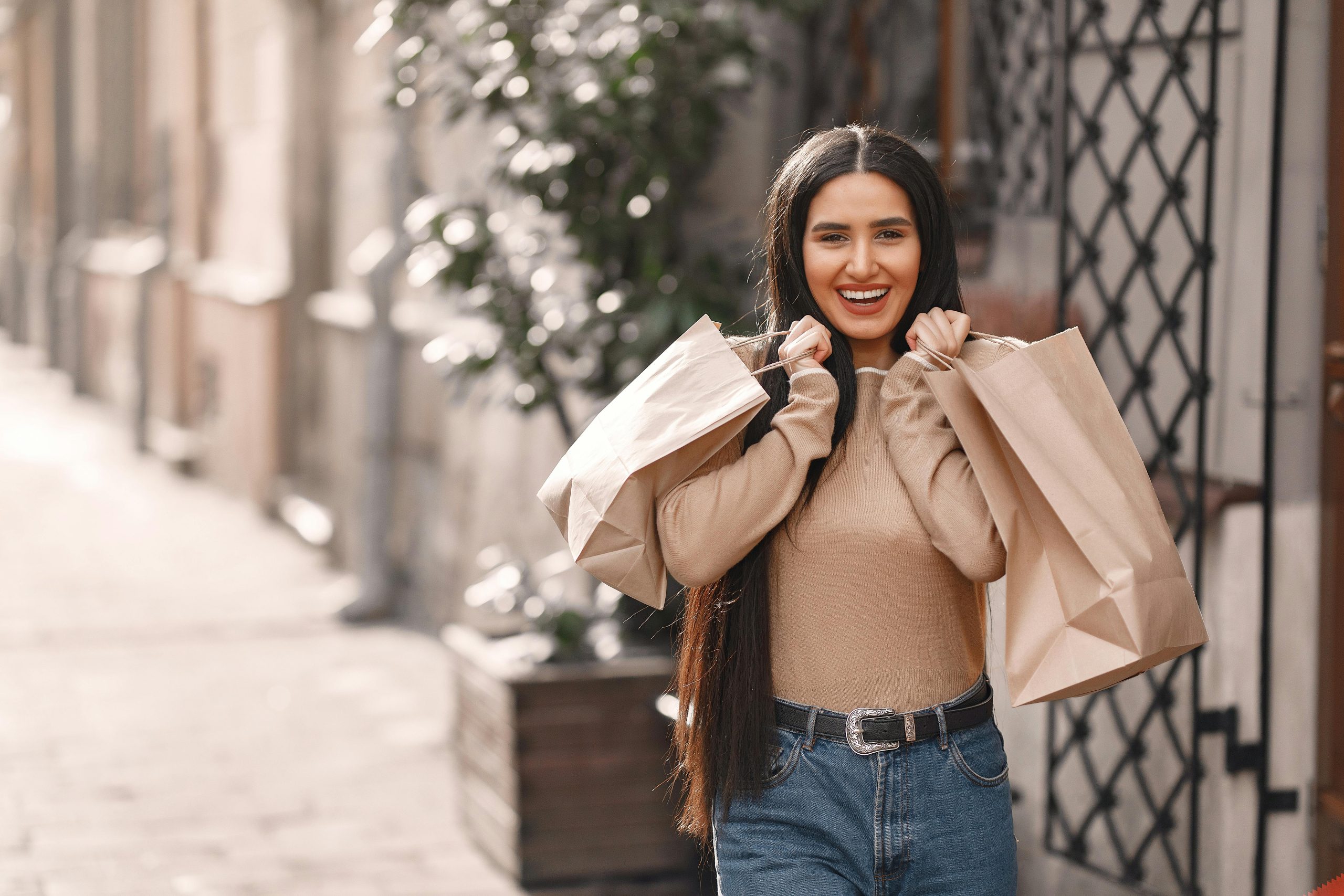 Cheerful young woman with shopping bags enjoying a sunny day outdoors.