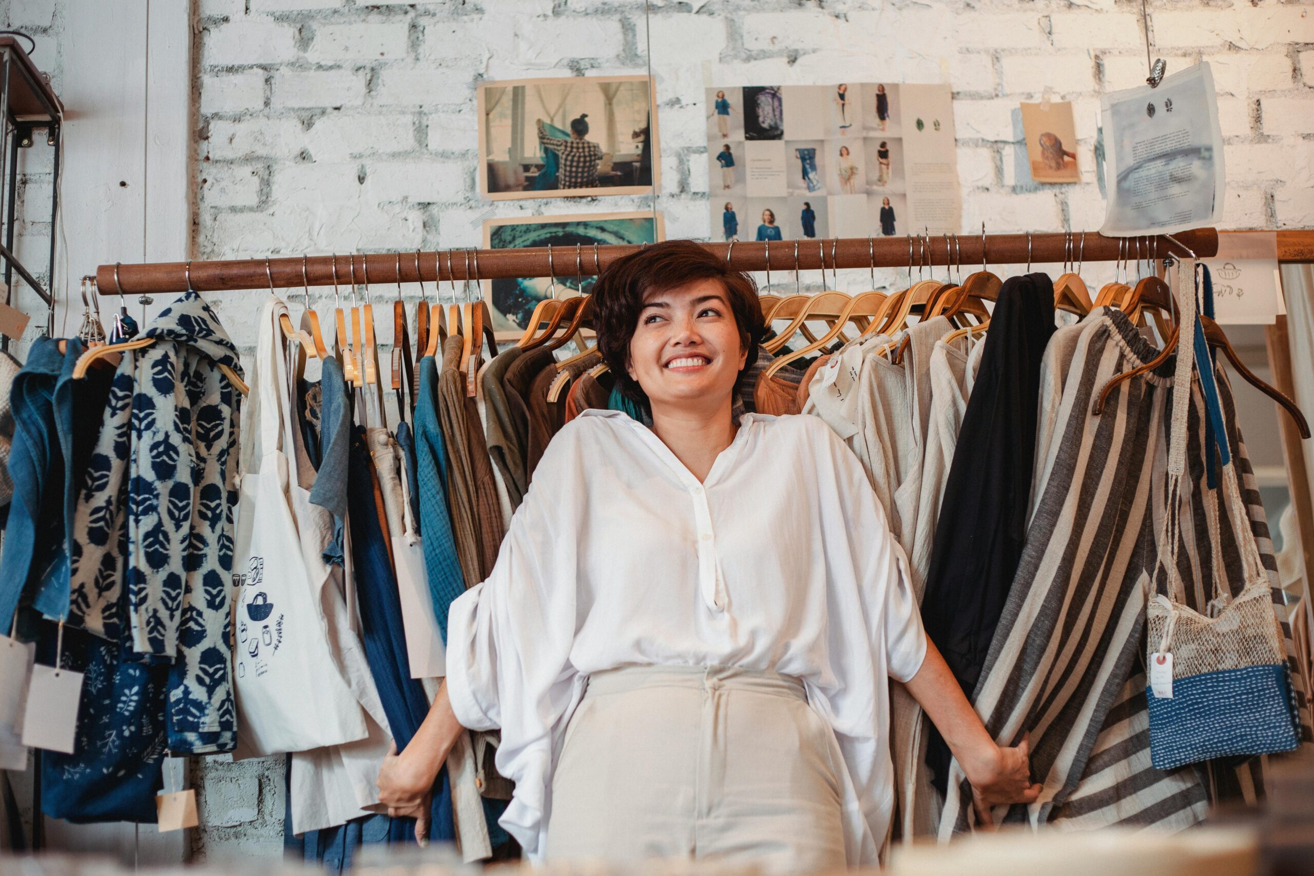 Cheerful woman shopping in a trendy fashion boutique with various stylish garments.